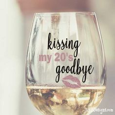 a wine glass that says kissing my 20's goodbye with lipstick on the bottom