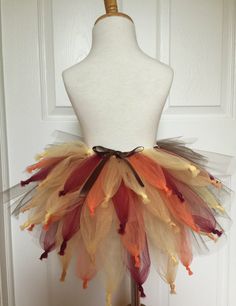 a mannequin wearing a multicolored tutu with feathers on it's head