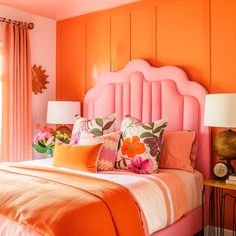 an orange and pink bedroom with flowers on the headboard, lamps, and bed