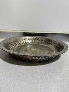 an antique silver plate with decorative designs on the rim and bottom, sitting on a white surface