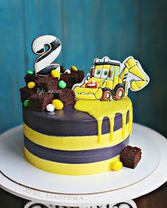 a yellow and purple cake with construction vehicles on it