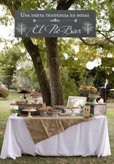 a table that has some food on it in the middle of a field with trees