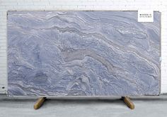 a large blue marble slab sitting on top of a wooden stand in front of a white brick wall