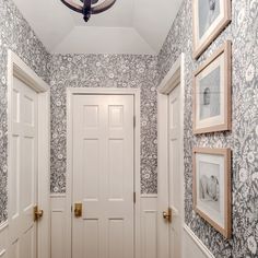 the hallway is decorated with blue and white wallpaper, framed pictures on the walls