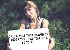 a girl holding a sign that says green was the color of the grass that you need to touch