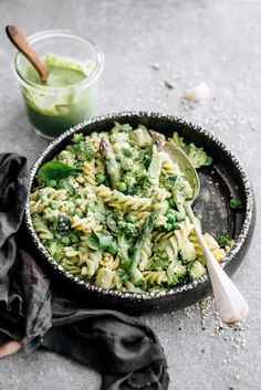 a bowl filled with pasta and broccoli next to a glass of green liquid