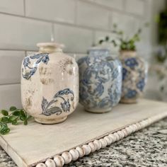 three blue and white vases sitting on top of a counter