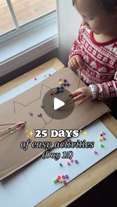 a little boy that is sitting at a table with some beads in front of him