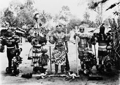 an old black and white photo of some people dressed in native american clothing, standing next to each other