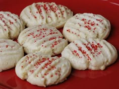 white cookies with red sprinkles on a red plate