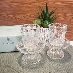 two clear glass candlesticks sitting on top of a table next to a box