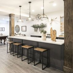 a kitchen with an island and stools in the center, surrounded by hanging lights