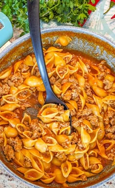 a large pot filled with pasta and meat in sauce on top of a marble table