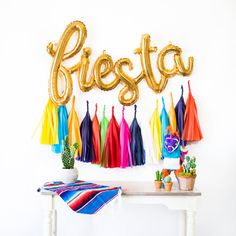 a table topped with balloons and tassels next to a sign that says fiesta