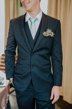 a man in a suit and tie standing next to a table