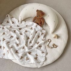 a teddy bear laying on top of a bed next to a blanket and toy rattler