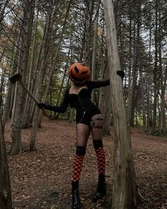 a woman dressed up as a witch in the woods with her hands on a tree