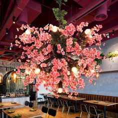 a dining room with tables and chairs covered in pink flowers hanging from the ceiling above them