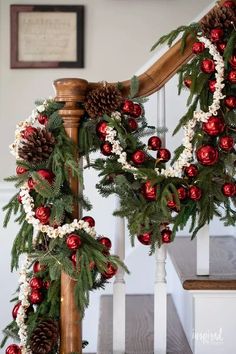 christmas garland on the banister with pine cones and red balls hanging from it's sides