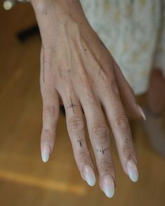 a woman's hand with cross tattoos on her left thumb and fingernails