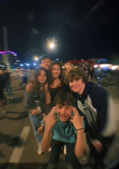 a group of young people standing next to each other on a street at night time