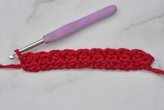 the crochet stitch is being worked on with a pink handled crochet hook