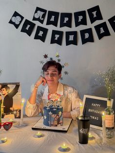 a man sitting at a table with a birthday cake in front of him and candles on the table