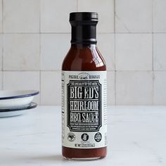 a bottle of bbq sauce sitting on top of a counter next to a plate