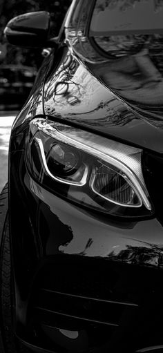 the front end of a black car parked next to another car