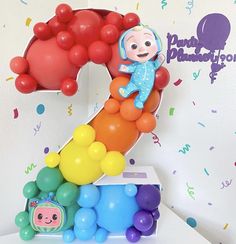 a birthday cake with balloons in the shape of a number one and a monkey on top