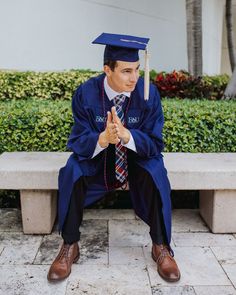 a man sitting on a bench wearing a graduation cap and gown