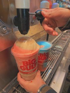 two people are filling cups with ice cream in an ice cream machine at a store