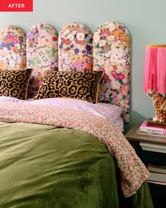 a bed with floral headboard and pillows on top of it next to a pink lamp