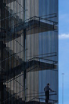 an airplane is flying in the air near a tall building with metal bars on it's sides