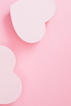 two heart shaped boxes sitting on top of a pink surface with one cut out in the shape of a heart