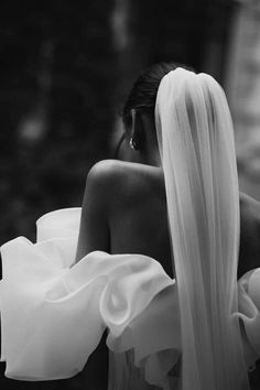 black and white photograph of a woman with long hair wearing a wedding veil, looking down at the ground