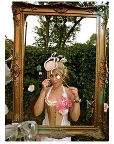 a woman in a corset is looking into a mirror with flowers on it