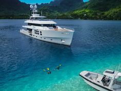 two people snorng in the water near a large white boat and some mountains