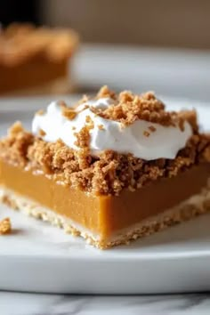 a slice of pumpkin pie on a white plate with whipped cream and crumbs