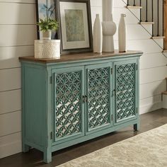 a blue cabinet sitting in front of a stair case next to a framed photo and vase