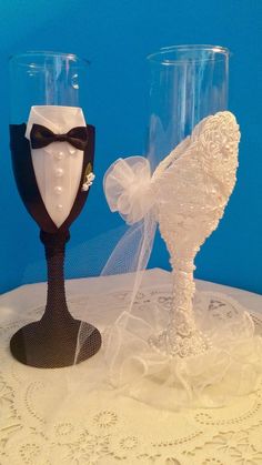 two wine glasses decorated to look like bride and groom's tuxedo hats