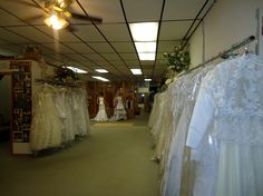 there are many wedding dresses on display in this store, and the bride is looking at her dress