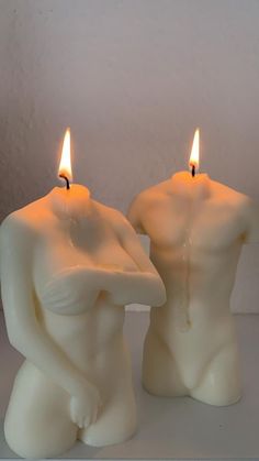 two candles that are sitting next to each other in the shape of people's torsos