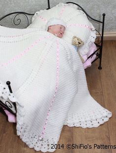 a baby wrapped up in a crochet blanket on top of a metal bed