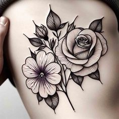 a woman's back with black and white tattoos on her stomach, holding flowers