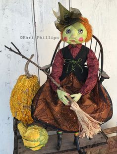 a creepy doll sitting on top of a chair next to some pumpkins and corn