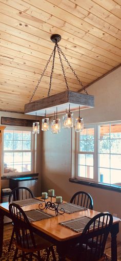 a dining room table with four chairs and a chandelier hanging from the ceiling