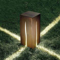 a wooden box sitting on top of a grass covered field next to a light beam