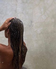 a woman standing under a shower head with water pouring from the faucet