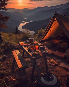 a table with food and drinks on it in front of a tent overlooking the mountains